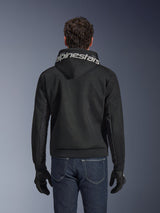 Alpinestars Chrome Superairflow Hoodie, zwarte motorhoodie, achteraanzicht met opvallende witte Alpinestars-branding op de capuchon, 3D technische mesh-constructie, gedragen met donkerblauwe jeans en zwarte handschoenen, geventileerde stedelijke motorkleding