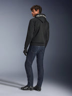 Alpinestars Chrome Superairflow Hoodie, zwart, achteraanzicht op mannelijk model, voorzien van witte Alpinestars-branding op de capuchon, gedragen met een donkere denim jeans en zwarte handschoenen, urban motoruitrusting ontwerp