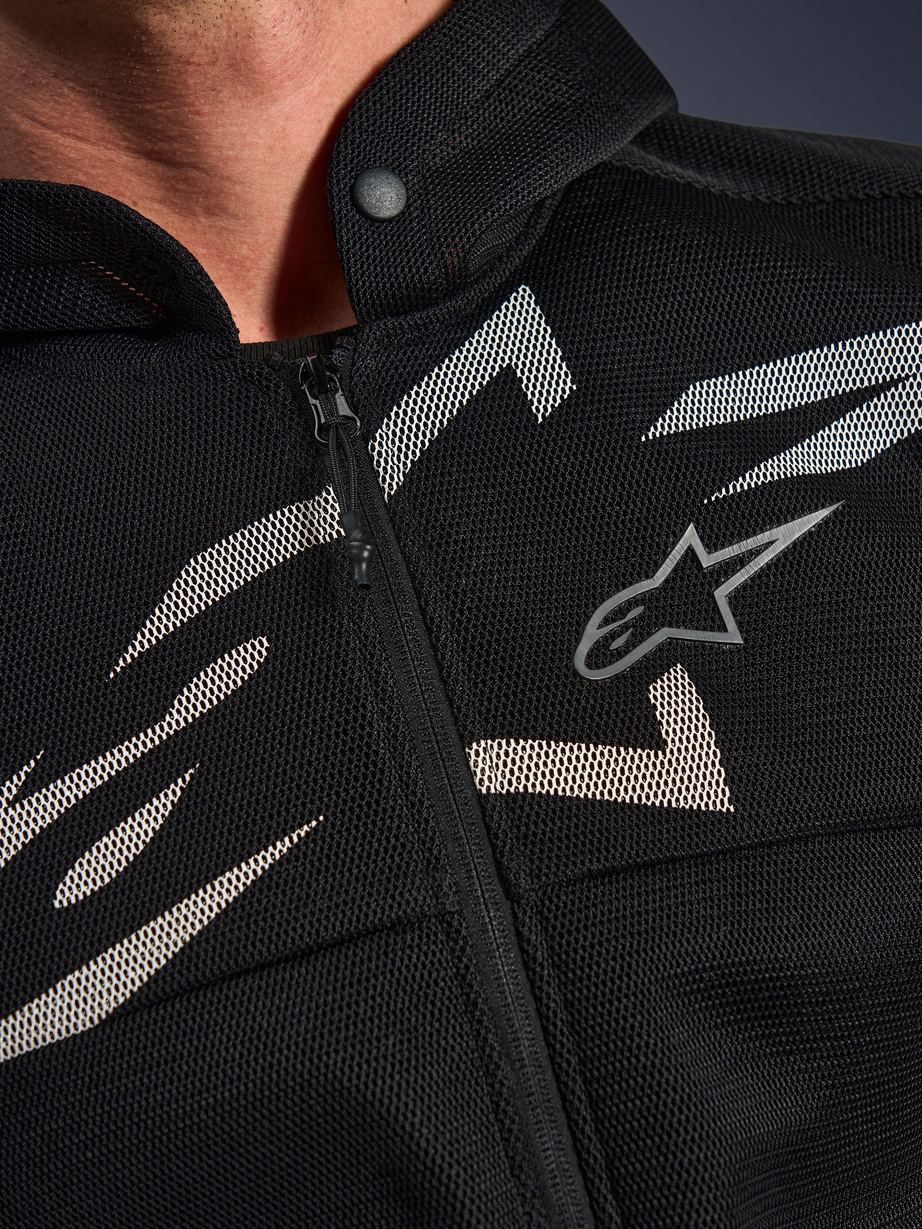 Alpinestars Chrome Superairflow Hoodie, motorhoodie, zwart met witte en grijze graphics, close-up van de borst met 3D technische mesh-constructie, ritssluiting aan de voorzijde en kraag met drukknoop, voorzien van Alpinestars logo