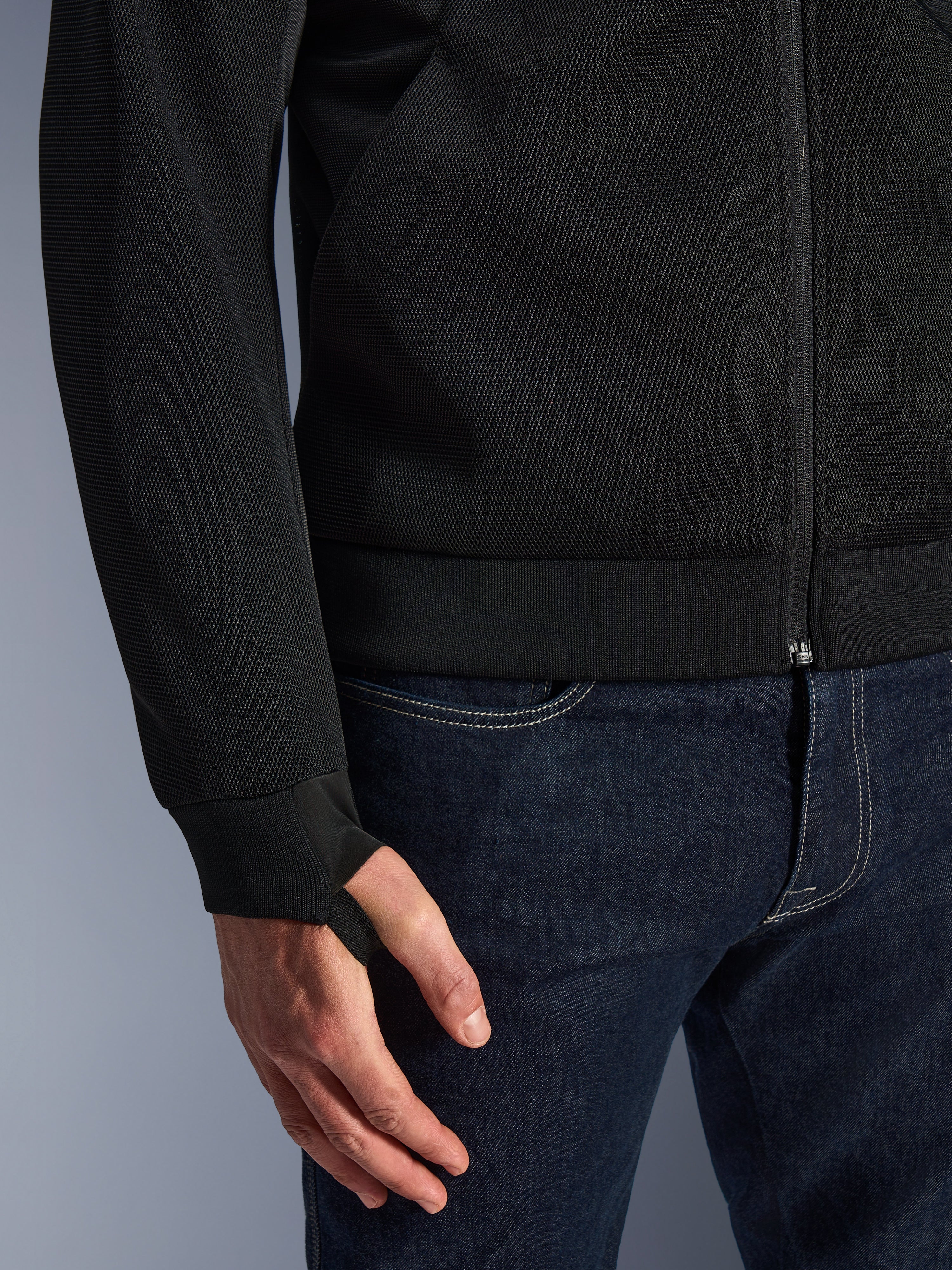 Alpinestars Chrome Superairflow Hoodie, zwart, close-up van zeer resistente 3D technische mesh-stof, voorzien van geribde stretch jersey manchet met elastische duimlus, gedragen met blauwe jeans