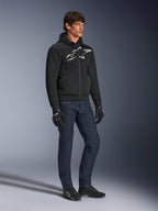 Alpinestars Chrome Superairflow Hoodie, zwart met wit en grijs logo, 3D-mesh geventileerde textielconstructie, gedragen met donkerblauwe denim jeans en zwarte motorhandschoenen, urban sportieve rijstijl