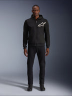 Alpinestars Chrome V2 Sport Hoodie, zwart-witte motorhoodie met een groot wit Alpinestars-logo op de borst, ritssluiting en capuchon, gedragen door een model met zwarte broek en laarzen, urban-stijl beschermende motorkleding.