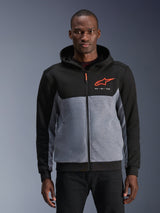 Alpinestars Chrome V2 Sport Hoodie, urban motorhoodie, zwart en grijs gemêleerd met Red Fluo accenten, voorzien van het Alpinestars-logo en "GOAL ONE VISION" tekst, casual beschermende kleding voor stadsgebruik, gedragen door een model tegen een grijze achtergrond.
