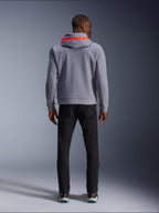 Alpinestars Chrome V2 Sport Hoodie, grijs gemêleerd met Red Fluo accenten, achteraanzicht met rood Alpinestars logo op de capuchon, gecombineerd met een zwarte broek, casual stedelijke rijstijl met beschermende tech fleece constructie