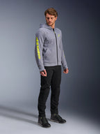 Alpinestars Chrome V2 Sport Hoodie, grijs gemêleerd en fluogeel, gedragen door een mannelijk model met zwarte broek en zwarte motorschoenen, met opvallende gele branding op de mouw en borst, casual stedelijke motorkleding