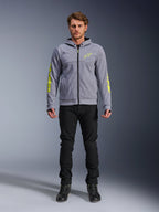Alpinestars Chrome V2 Sport Hoodie, grijs gemêleerd met fluorescerend gele accenten, stedelijke motorkleding, getoond met zwarte broek en zwarte motorschoenen, technische fleece met opvallende gele branding op de mouwen en borst, casual straatstijl voor tijdens het rijden