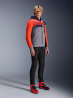 Alpinestars MM93 Chrome V2 Sport Hoodie, urban motorhoodie, grijs gemêleerde body met donkerblauwe borst en felrode fluo mouwen, voorzien van het 93-logo op de borst, gedragen door een model met slim-fit zwarte broek en bijpassende rode en blauwe hoge motorschoenen, moderne atletische pasvorm voor rijden op de weg