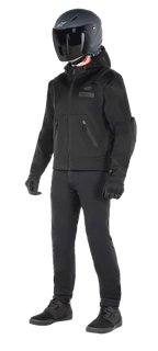 Alpinestars Moflow Air Tech Hoodie, urban motorhoodie, zwart, gedragen door een motorrijder met een matzwarte helm, zwarte handschoenen en motorbroek, voorzien van een volledige mesh-constructie voor optimale ventilatie, zakken met ritssluiting en subtiele logo's op de borst, strak casual ontwerp voor rijden in de stad bij warm weer.