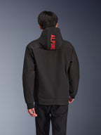 Alpinestars Radium Tech Hoodie, urban motorjas, zwart met felrode branding, achteraanzicht met verticale 'ALPINE'-tekst op de capuchon, 3-laags technische shell met geribde manchetten, modern atletisch ontwerp