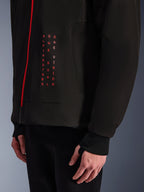 Alpinestars Radium Tech Hoodie, stedelijke motorjas, zwart en felrood, close-up van graphic aan de voorzijde met verticale rode tekst "ALPINESTARS ONE GOAL ONE VISION", rode rits en geribde manchet met duimgat.
