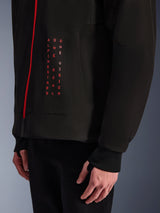 Alpinestars Radium Tech Hoodie, Urban Motorcycle Jacket, Black and Bright Red, close-up of front graphic with vertical red text "ALPINESTARS ONE GOAL ONE VISION", red zipper, and ribbed cuff with thumbhole.