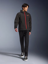 Alpinestars Radium Tech Hoodie in Black Bright Red, urban motorcycle jacket worn by a model, featuring a red front zipper and chest logo, styled with black pants and sneakers for a modern commuting look.