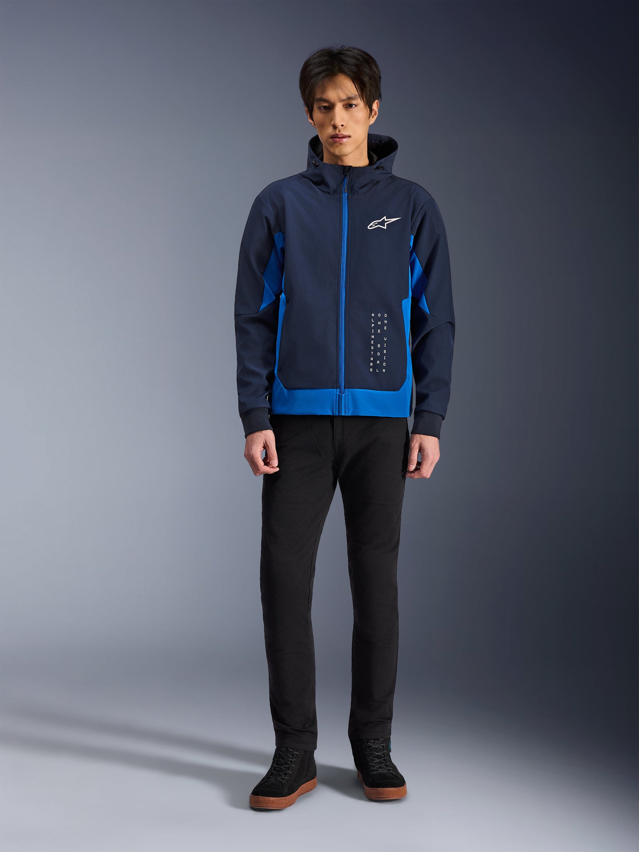 Alpinestars Radium Tech Hoodie, Night Navy and Royal Blue urban motorcycle hoodie, windproof technical shell, casual streetwear design worn with black pants and high-top sneakers, features white logo branding on the chest.