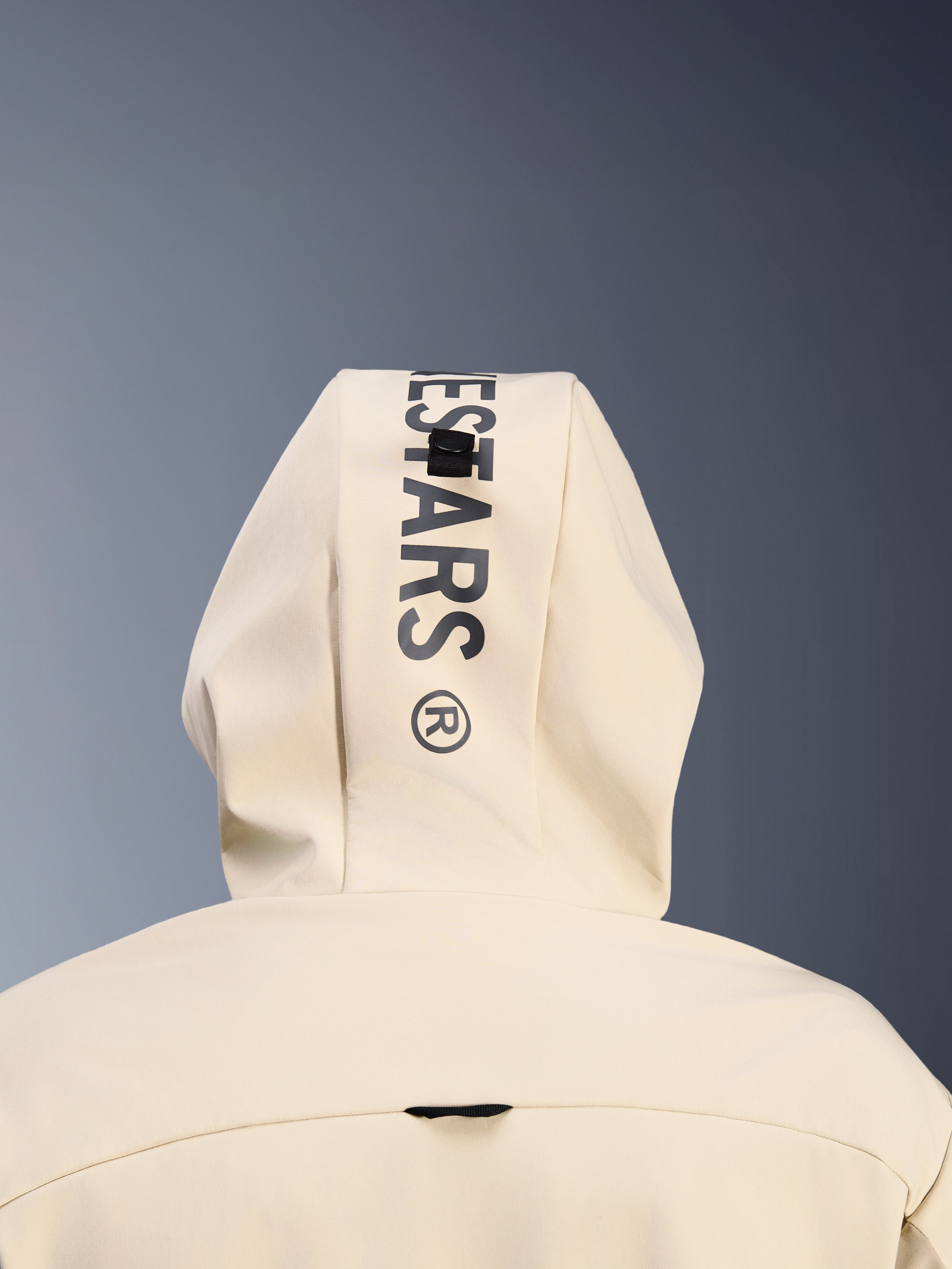 Alpinestars Radium Tech Hoodie in Mastic Aluminum, close-up achteraanzicht van de capuchon met verticale zwarte Alpinestars-branding en het bevestigingslussysteem voor de capuchon, detail van stedelijke motorkleding
