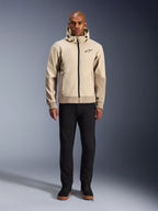 Alpinestars Radium Tech Hoodie in Mastic Aluminum, stedelijke motorhoodie gedragen door een mannelijk model met zwarte broek en zwarte laarzen, voorzien van een zwarte ritssluiting over de volledige lengte, klein logo op de borst, atletische pasvorm voor stadsritten