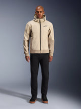 Alpinestars Radium Tech Hoodie in Mastic Aluminum, stedelijke motorhoodie gedragen door een mannelijk model met zwarte broek en zwarte laarzen, voorzien van een zwarte ritssluiting over de volledige lengte, klein logo op de borst, atletische pasvorm voor stadsritten