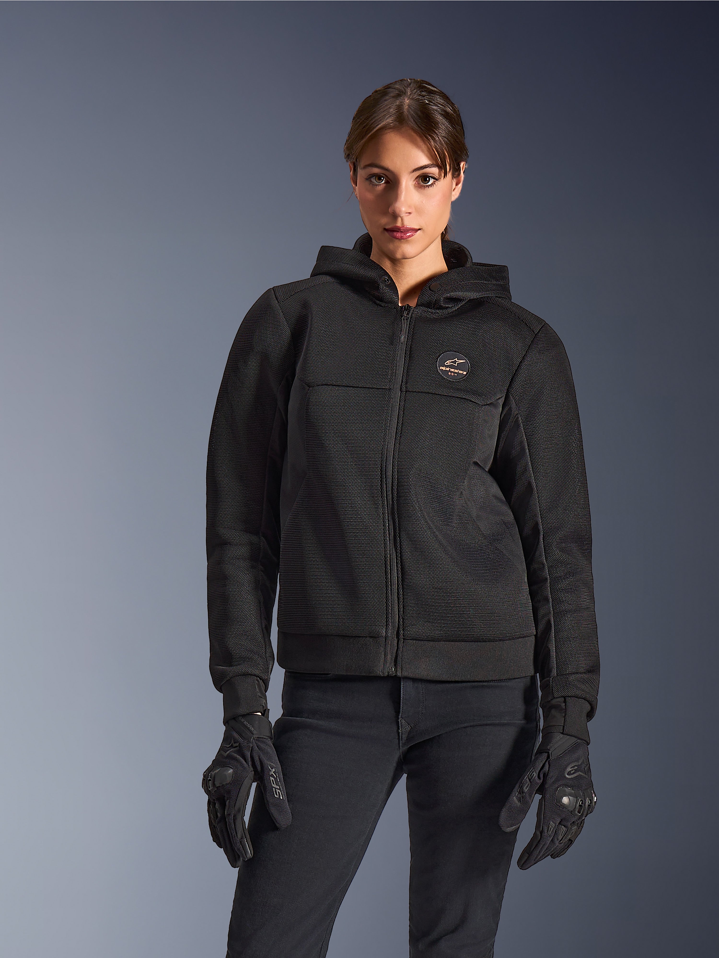 Alpinestars Stella Chrome Superairflow Hoodie, dames motorhoodie, zwart, jack met capuchon met borstlogo en centrale ritssluiting, gedragen met zwarte handschoenen, strak modern ontwerp voor stadsritten