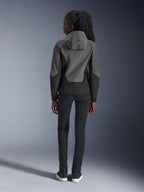 Alpinestars Stella Radium Tech Hoodie voor dames, donkergrijs en zwart, achteraanzicht met 'ALPIN'-branding op de capuchon, gecombineerd met een zwarte slim-fit broek en zwarte sneakers, stedelijke motorkleding