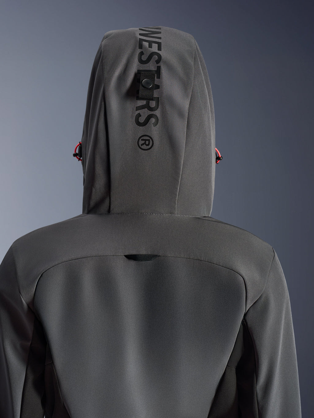 Alpinestars Stella Radium Tech Hoodie voor dames, Deep Gray Black, close-up achteraanzicht met de capuchon met verticale branding en bevestigingslus, rode trekkoord-accenten, duurzame 3-laags winddichte textielconstructie voor stedelijk motorrijden.