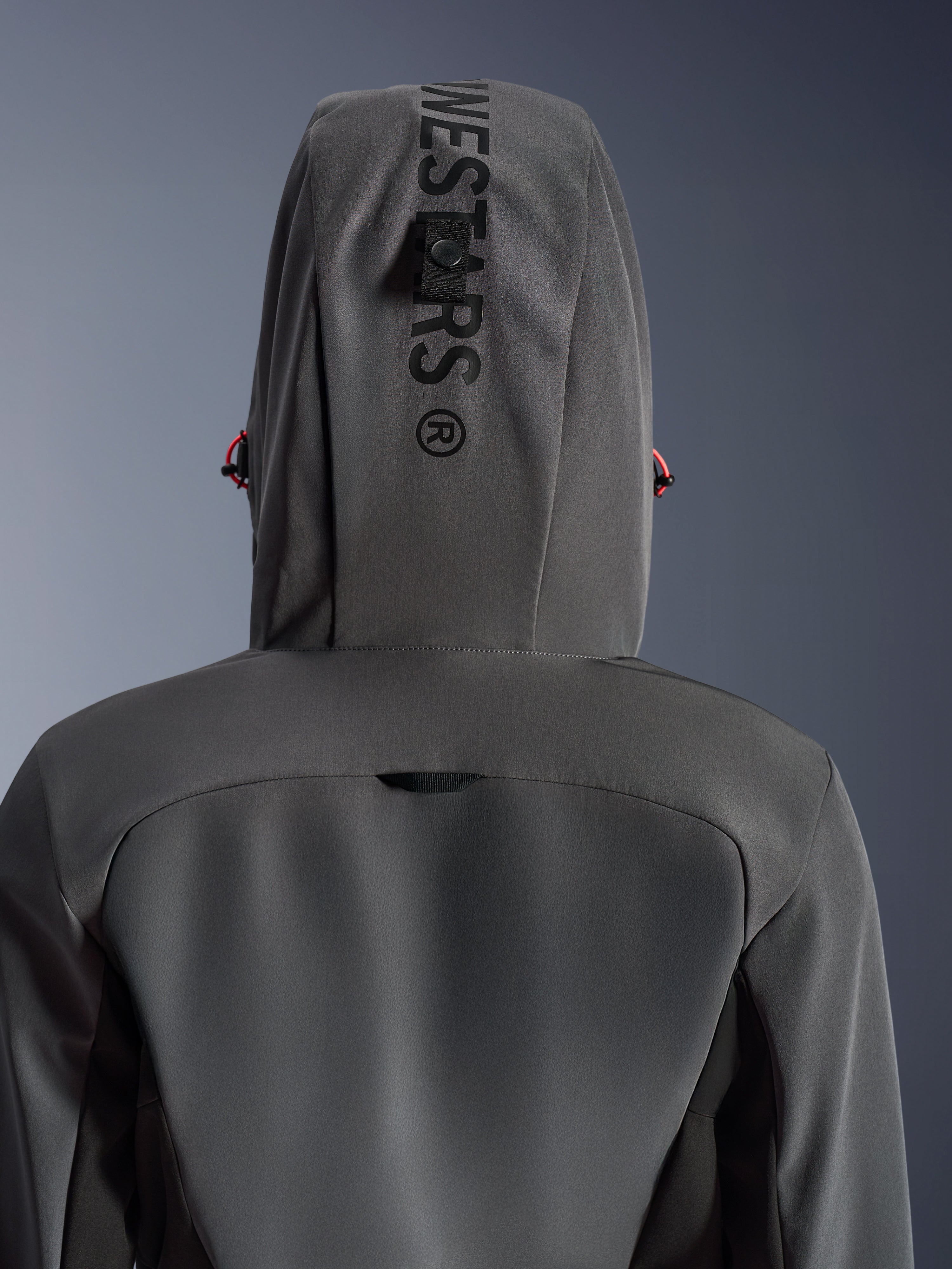 Alpinestars Stella Radium Tech Hoodie voor dames, Deep Gray Black, close-up achteraanzicht met de capuchon met verticale branding en bevestigingslus, rode trekkoord-accenten, duurzame 3-laags winddichte textielconstructie voor stedelijk motorrijden.