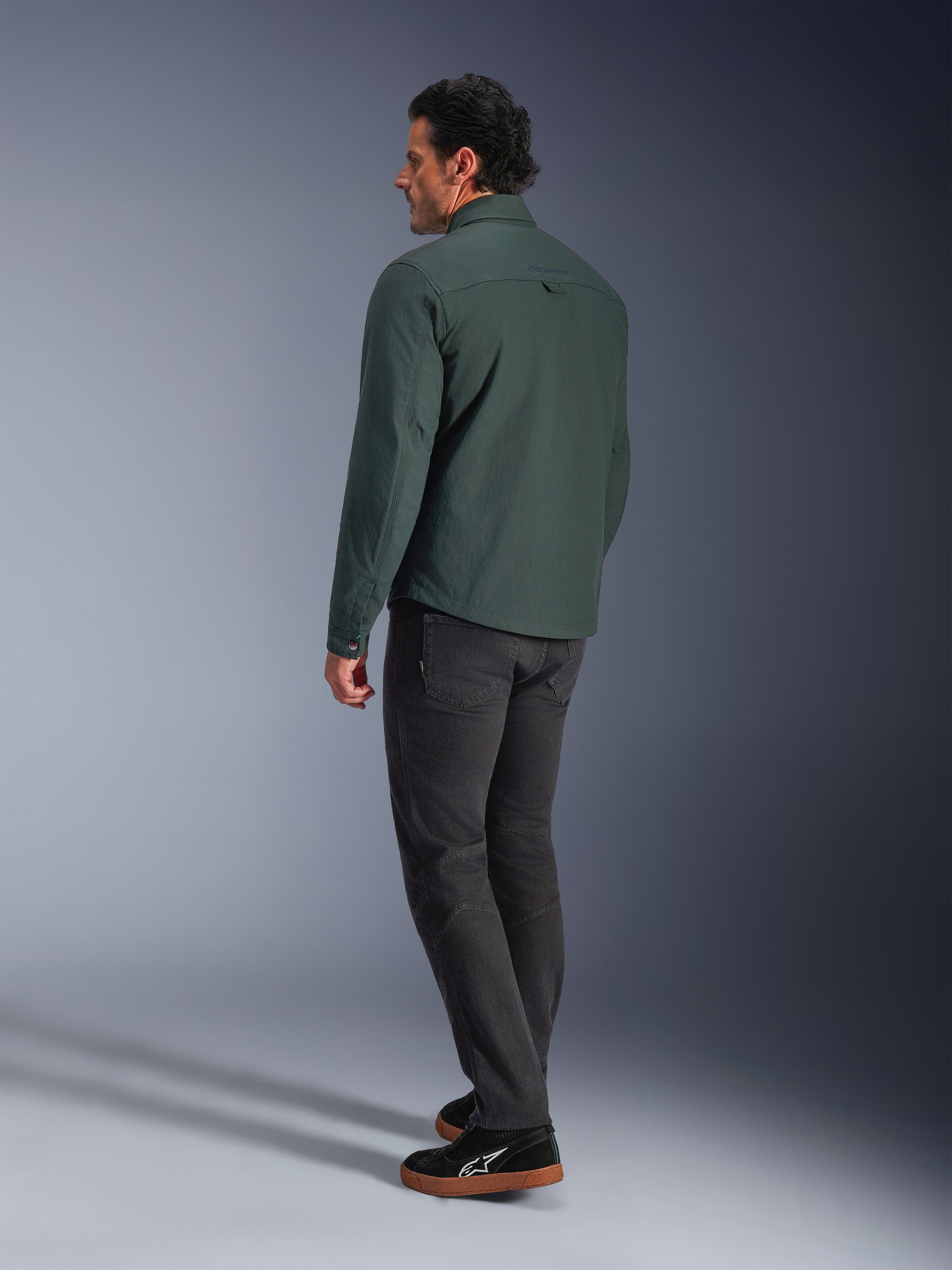 Alpinestars Bryon Water Resistant Overshirt, Dark Emerald groen, achteraanzicht van een urban motorjas, gedragen met een donkere broek en zwarte sneakers, modern op werkkleding geïnspireerd ontwerp