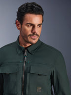 Alpinestars Bryon Water Resistant Overshirt in Dark Emerald, close-up portret van een man die de stedelijke motorjas draagt, gewaxte canvas textuur, voorrits met subtiele teal accenten, cargozakken op de borst en merklogo-patch.