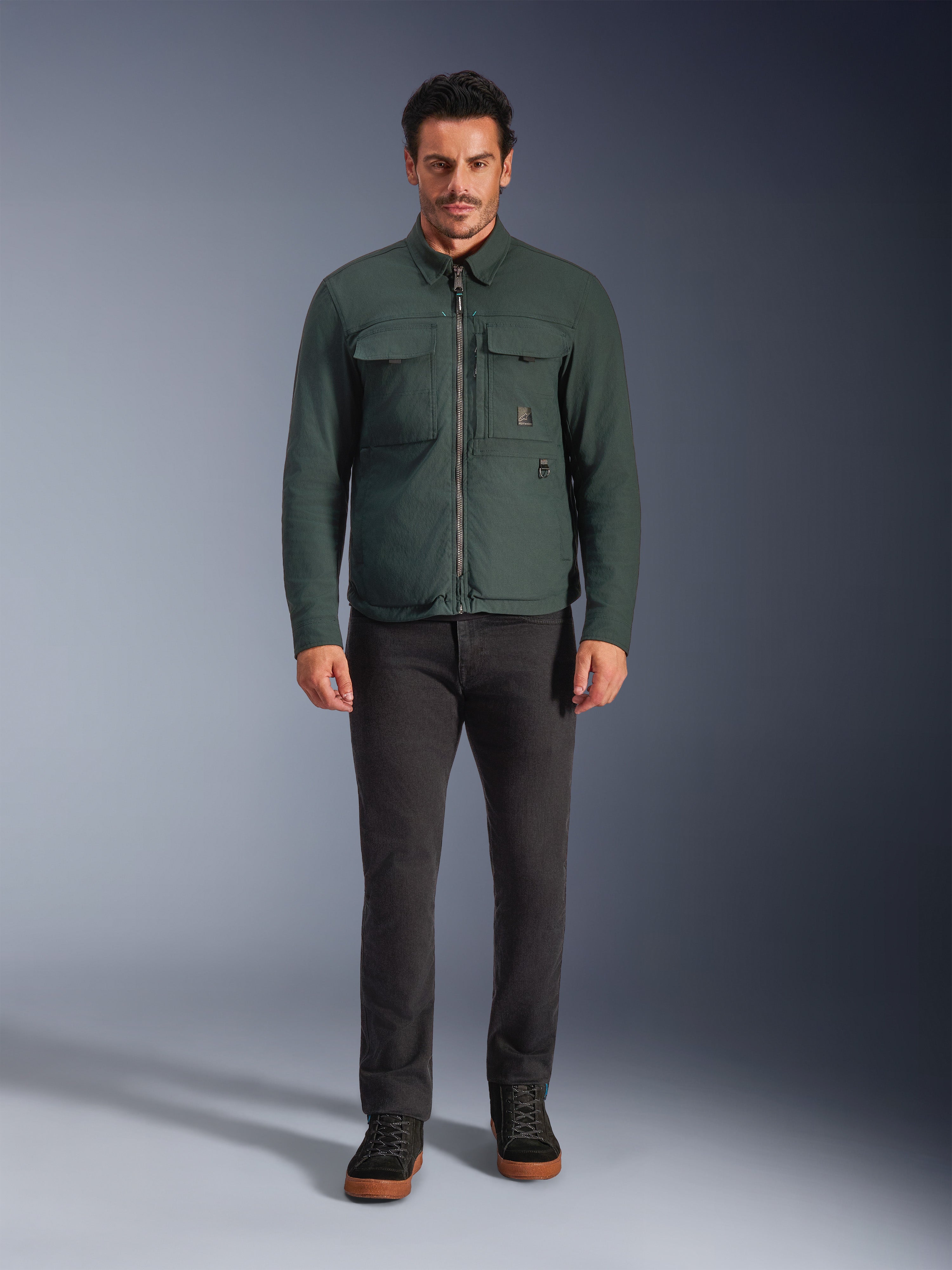 Alpinestars Bryon WR Overshirt, waterbestendig motorjack, Dark Emerald, gedragen met zwarte broek en zwarte laarzen, voorzien van een gewaxt canvas constructie, cargozakken op de borst en een modern urban design.