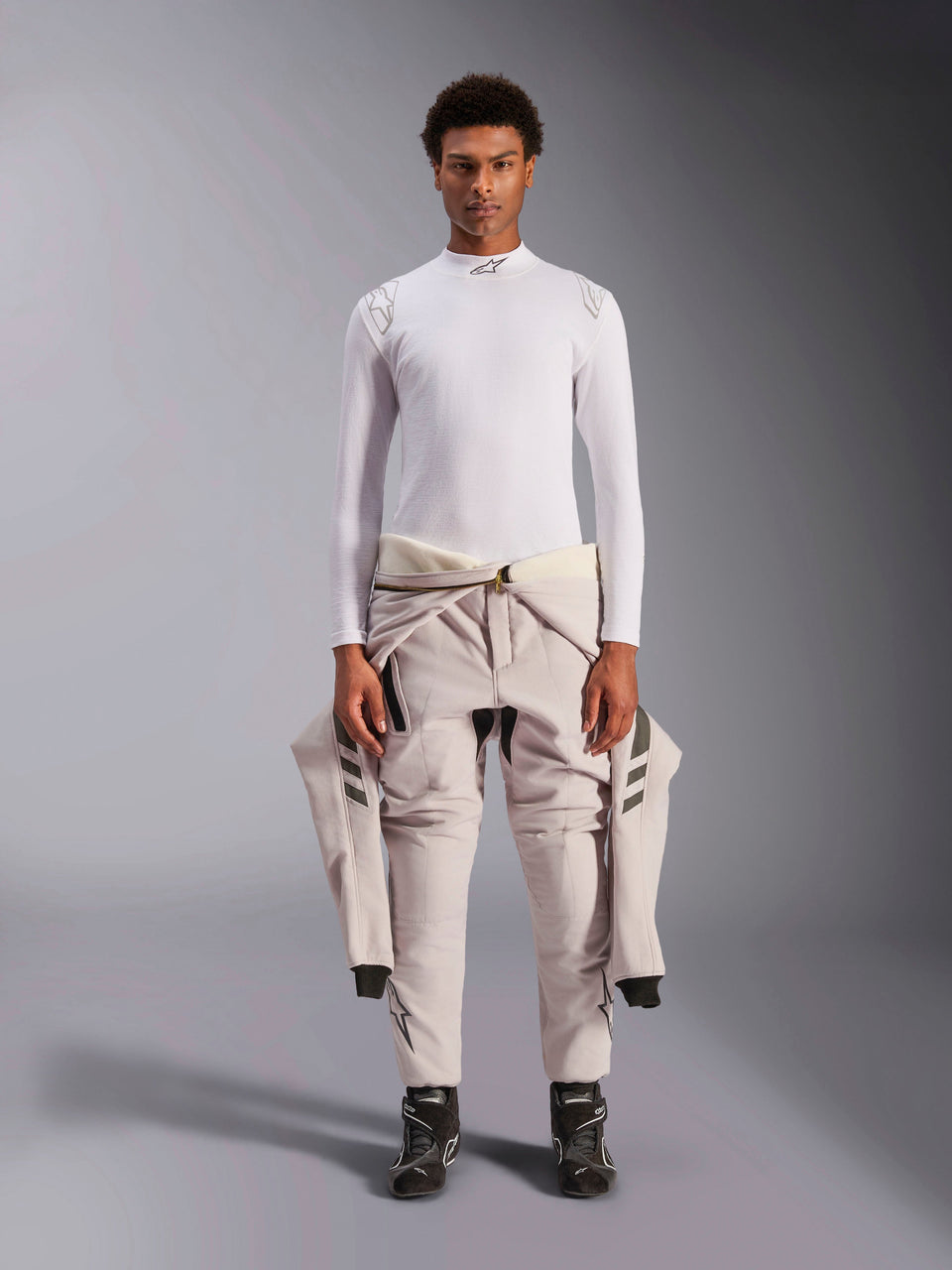 Alpinestars ZX Evo V3 Top, Long Sleeve, White, auto racing base layer worn with a light-colored racing suit tied around the waist and black racing boots, featuring a mock neck with logo and shoulder branding, professional flame-resistant motorsport underwear