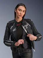 Alpinestars Stella Dusk leren jas voor dames, zwart en wit, vrouwelijk model toont de interne gewatteerde thermische voering en Tech-Air Ready label, hoogwaardig runderleer met wit sterlogo en 'RACING AHEAD' branding op de mouw