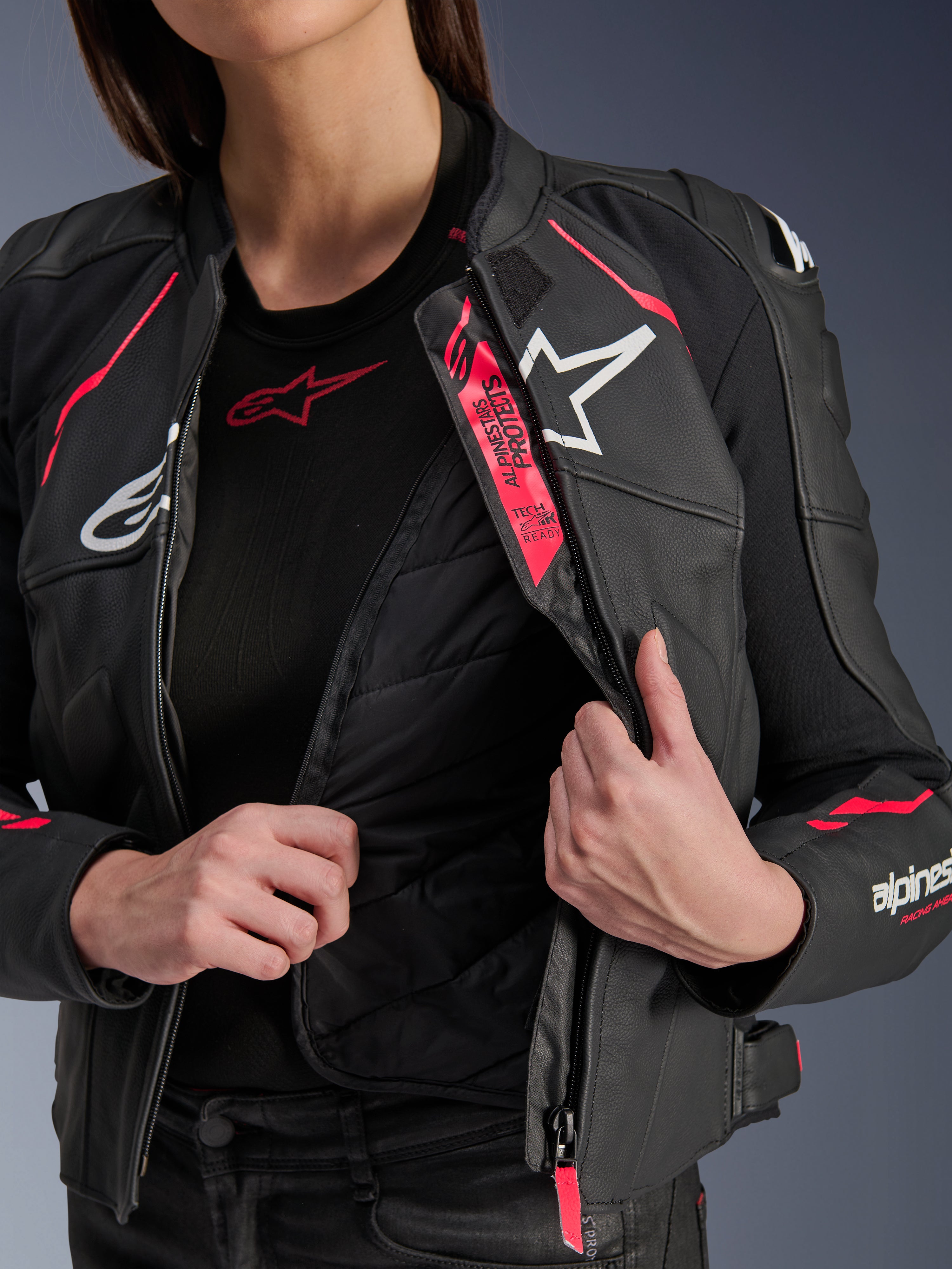Alpinestars Stella Dusk leren damesjas, zwart, Diva roze en wit, leren motorjas geopend om de interne doorgestikte thermische voering en Tech-Air Ready-branding te tonen, witte logo's en levendige roze accenten.