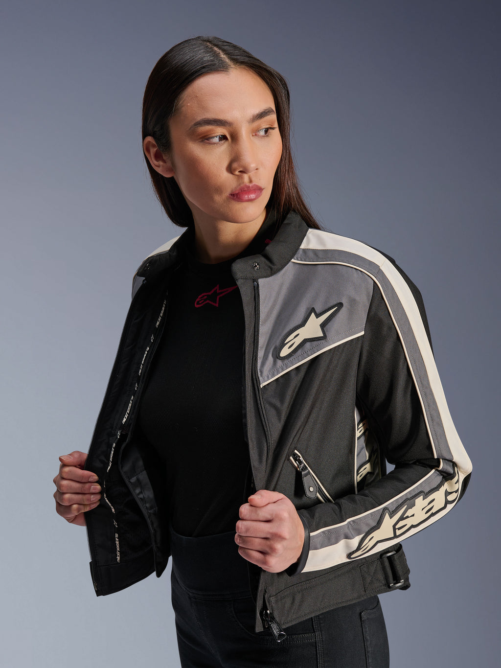 Alpinestars Stella T-Dyno WR damesjas, textiele motorjas, zwart, donkergrijs en ecru, vintage-geïnspireerd design met sportieve strepen en logo's op de borst en mouwen, gedragen door een model, urban rijuitrusting