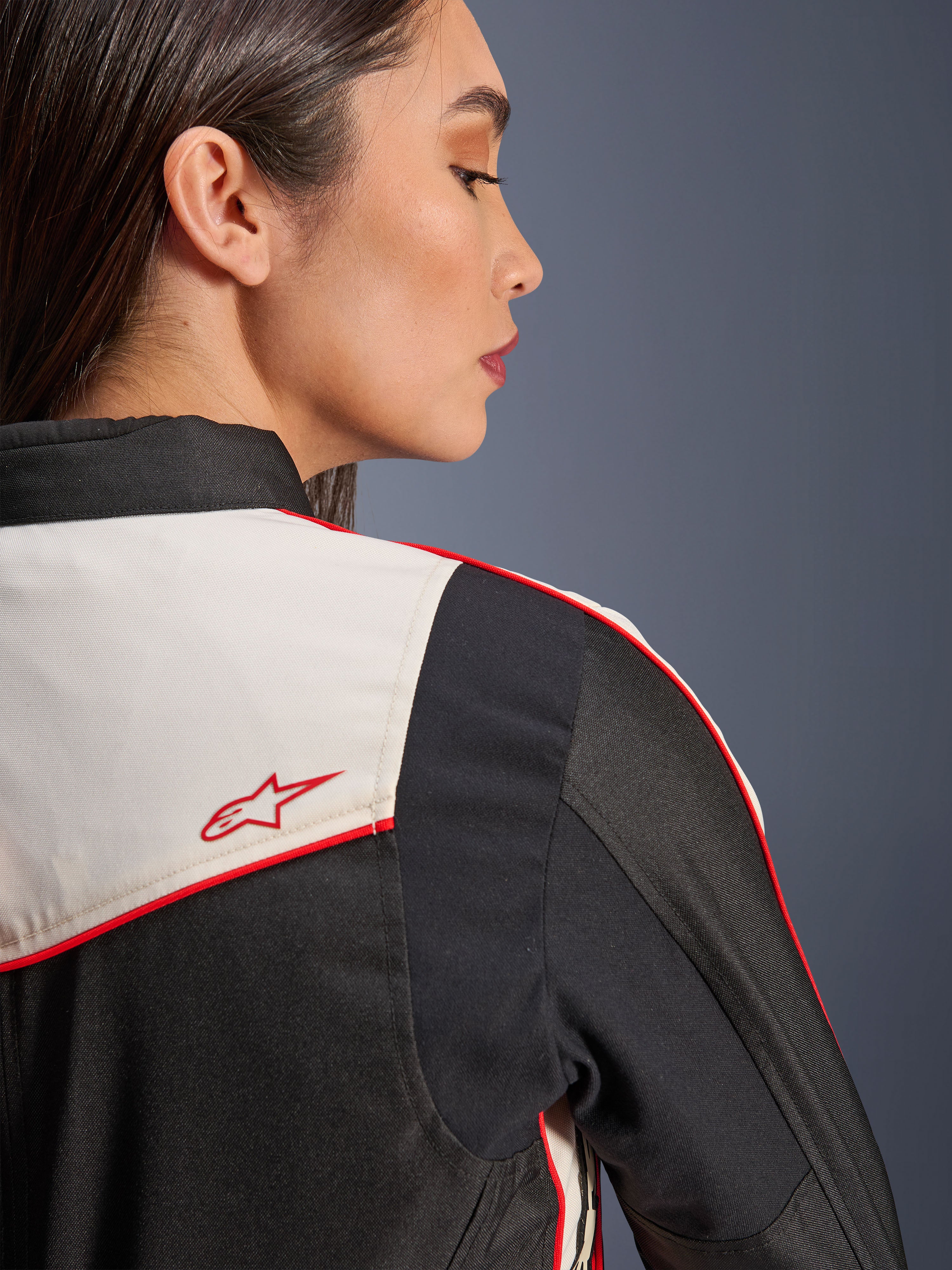 Alpinestars Stella T-Dyno WR jas in Black Ecru Bright Red, close-up van de schouder en rug, met ecru panelen, rode biezen en een rood Alpinestars sterlogo, textiele motorkleding voor dames
