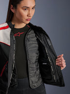 Alpinestars Stella T-Dyno WR Jas, motorjas voor dames, Black Ecru en Bright Red, close-up binnenaanzicht met het uitneembare gewatteerde thermische vest, waterdicht binnenvak en 'ALPINESTARS PROTECTS' branding.