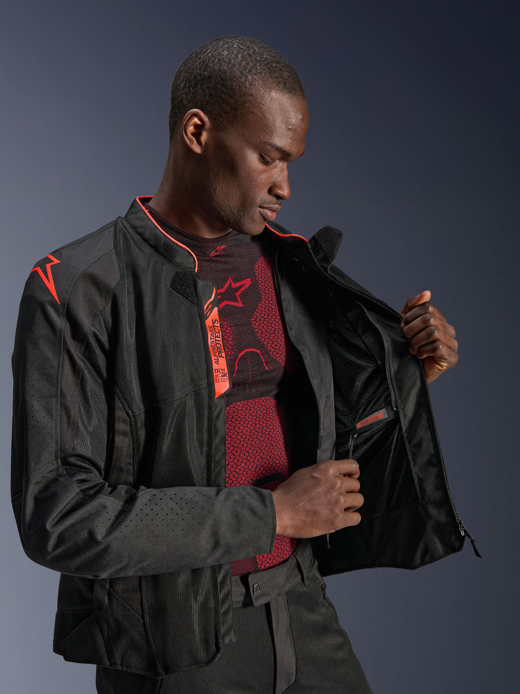 Alpinestars Viper Air V4 Jas, Black Red Fluo, motorjas met tech mesh panelen, mannelijk model toont het waterdichte binnenvak en de binnenvoering, voorzien van rode fluo accenten en Tech-Air Ready branding.