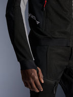 Alpinestars Troop-Air Pro Jas, premium gepantserde luchtjas, zwart met asgrijs en felrood, voorzien van 2D tech mesh-constructie voor ventilatie, asgrijze mouwpanelen, rood ritsaccent en geïntegreerde duimgatmanchetten, gedragen met bijpassende broek.