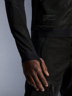 Alpinestars Troop-Air jas, zwart, close-up van de technische mesh-constructie, merkpatch met technische tekst en mouw met geïntegreerde duimgatlus, urban zomer motorjas met high-airflow ontwerp