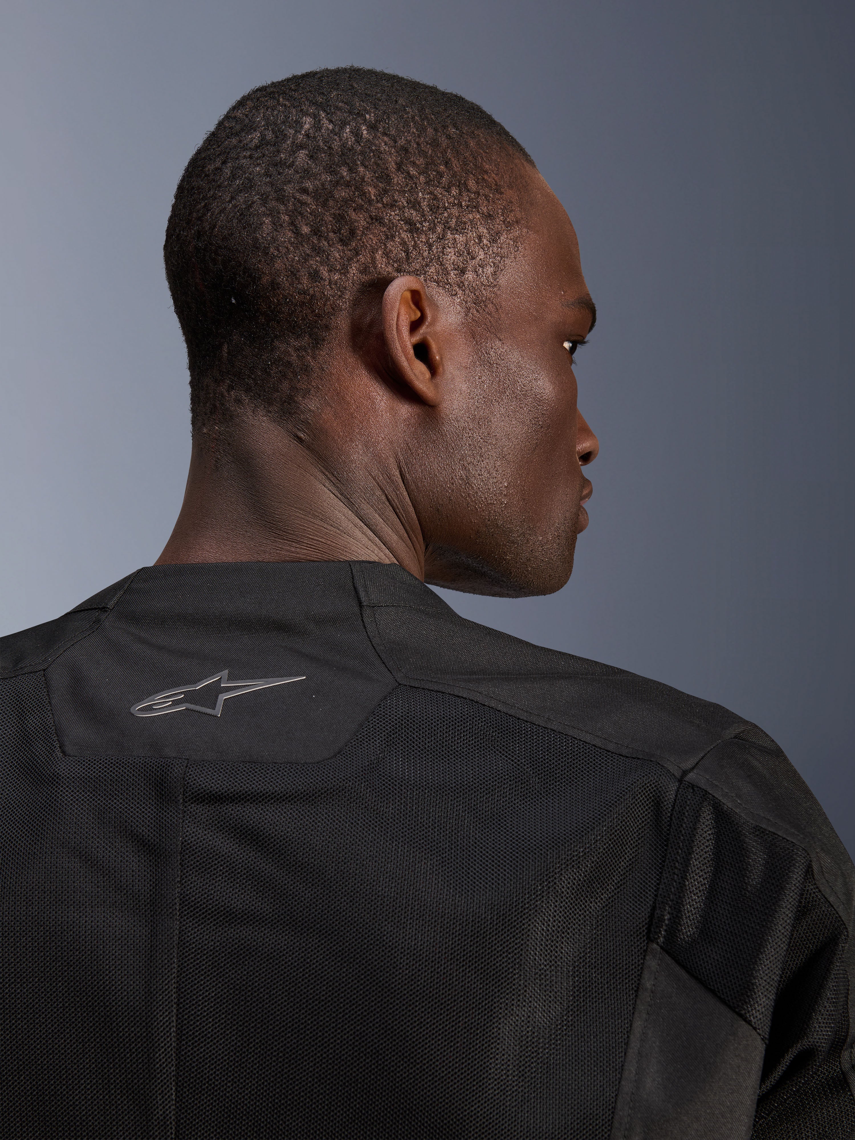 Alpinestars C-1 Air Jacket, zwarte motorjas, close-up van de achterkant met ademende tech mesh panelen en een reflecterend Alpinestars-logo op de kraag, urban motorkleding