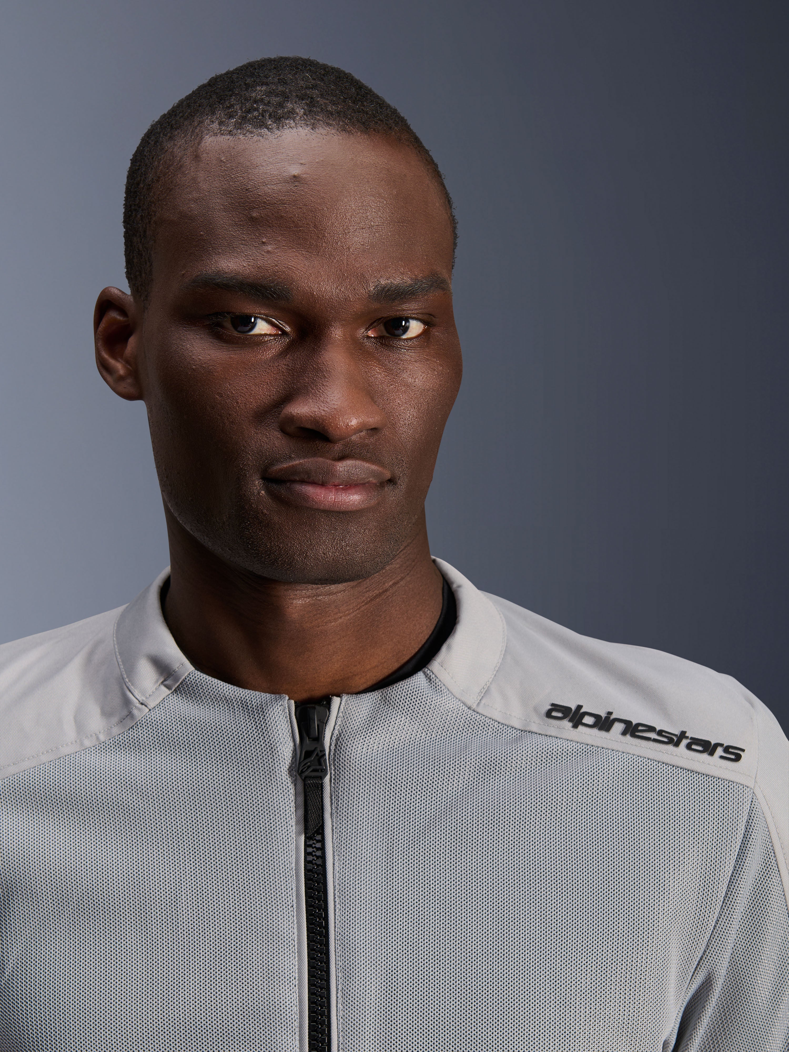 Alpinestars C-1 Air Jacket in zilver en grijs, close-up portret van een mannelijke rijder, voorzien van technische mesh-panelen en zwarte branding op de schouder, urban contemporary motorkleding