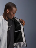 Alpinestars C-1 Air Jacket in zilver, mannelijk model opent de voorzijde van de motorjas om de zwarte tech mesh binnenvoering en waterdichte binnenzak met ritssluiting te tonen.