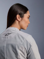 Vrouw die de Alpinestars Stella C-1 Air Jas in Silver draagt, close-up zij-achteraanzicht met het zwarte Alpinestars-logo, tech mesh ventilatiepanelen en een strak, eigentijds stedelijk motorontwerp
