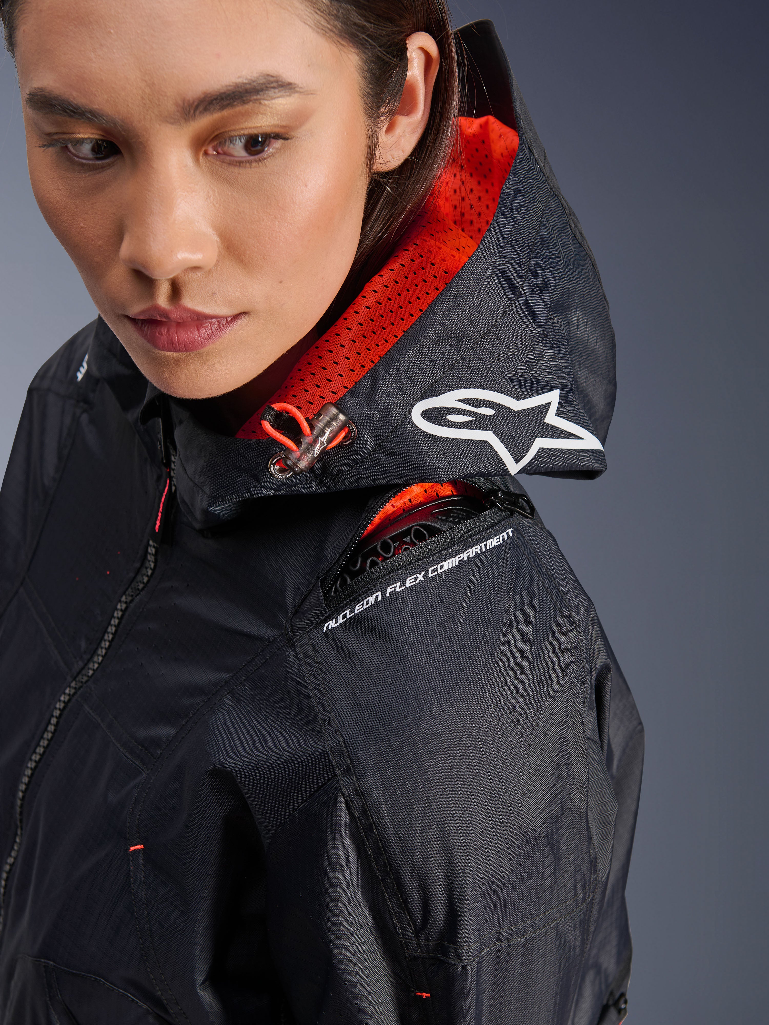 Alpinestars Molly Air Jacket, dames motorjas, Zwart en Fluo Coral, close-up van de schouder met focus op het Nucleon Flex protectorcompartiment en wit Astars logo op de capuchon, urban motorkleding met ripstop stof