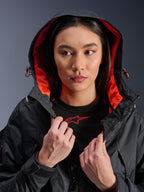 Alpinestars Molly Air Jas, motorjas voor dames, zwart en fluo coral, model draagt de capuchon omhoog en toont de opvallende koraalrode mesh-voering, ripstop textielstof, urban hedendaagse motorkleding