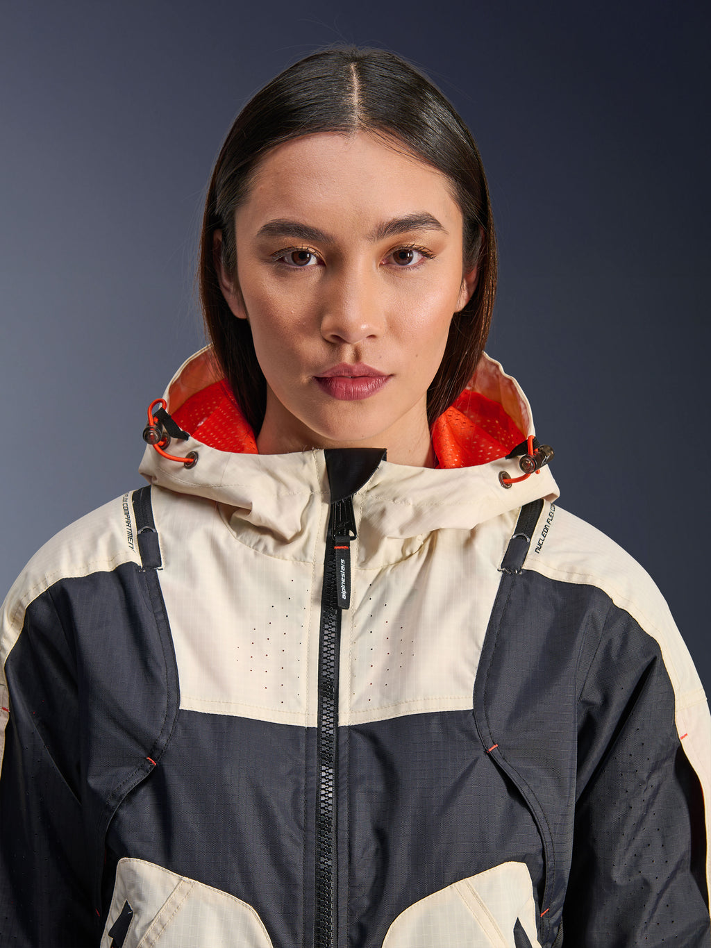 Alpinestars Molly Air Jacket, textiele motorjas voor dames, Black Almond, close-up vooraanzicht van een model dat de jas draagt met een ontwerp met crème en zwarte panelen, feloranje met mesh gevoerde capuchon en laser-geperforeerde details op de borst