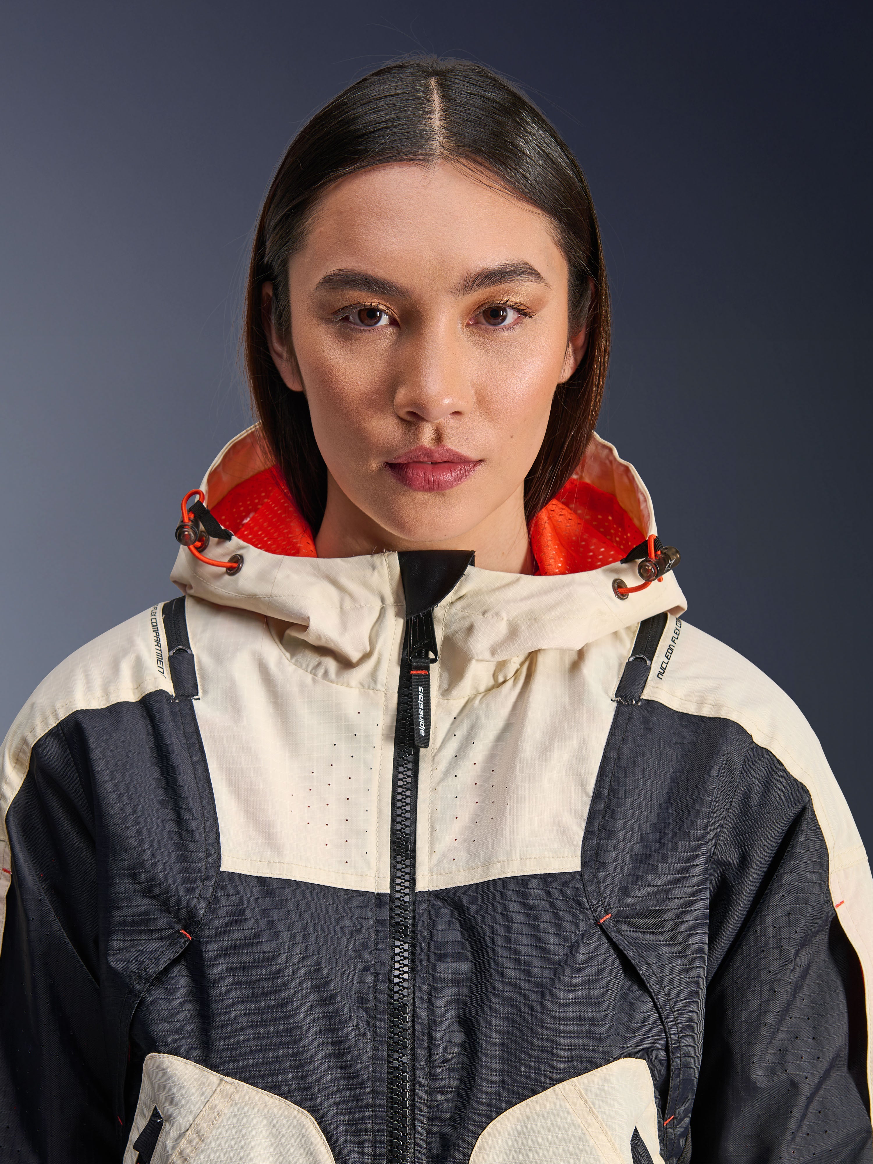 Alpinestars Molly Air Jacket, textiele motorjas voor dames, Black Almond, close-up vooraanzicht van een model dat de jas draagt met een ontwerp met crème en zwarte panelen, feloranje met mesh gevoerde capuchon en laser-geperforeerde details op de borst