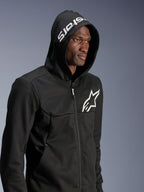 Alpinestars Chrome V2 Sport Hoodie, zwarte urban motorhoodie gedragen door model met de capuchon op, wit sterlogo op de borst en witte stars branding op de capuchon, tech fleece constructie, casual motor streetwear