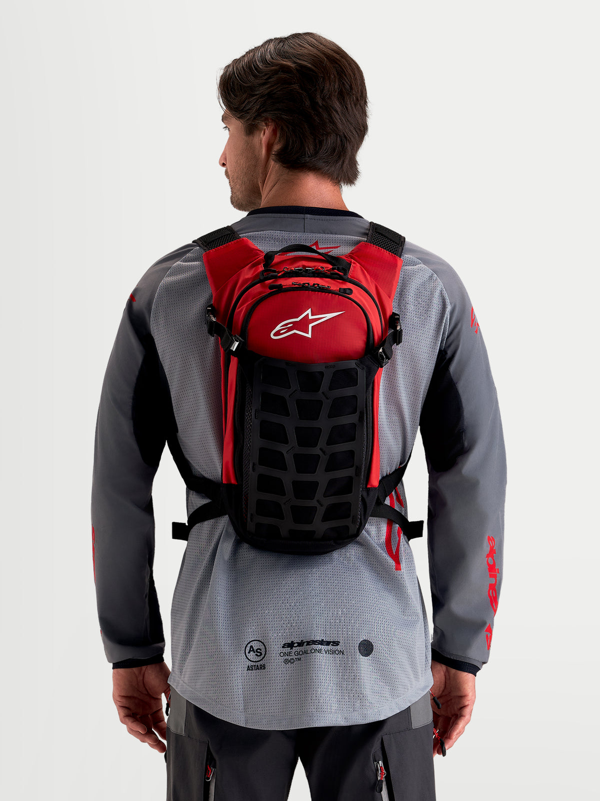 Alpinestars AT-9 Rugzak, motocross rugzak, zwart en rood, gedragen door een model van de achterkant met een lichtgewicht textielconstructie en een gewatteerd harnassysteem