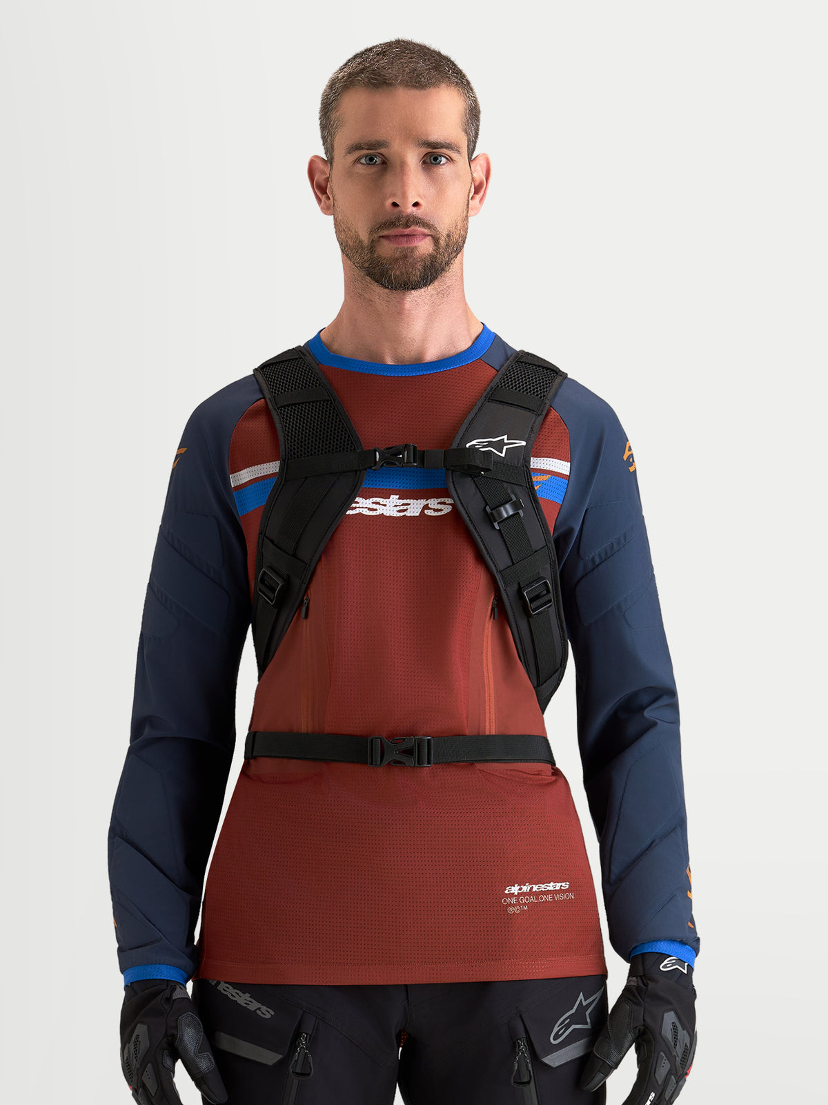 Alpinestars AT-9 rugzak, motocrossrugzak in zwart en diepgrijs, vooraanzicht gedragen door een mannelijk model met gewatteerd schouderharnas en borstgespsysteem