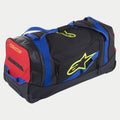 Alpinestars Komodo Travel Bag, verrijdbare gear bag, zwart met blauwe, rode en fluorgele accenten, voorzien van blauwe handvatten, een rood zijpaneel en fluoriserende gele logo's, duurzame constructie met wielen voor het vervoeren van motorcross- en race-uitrusting