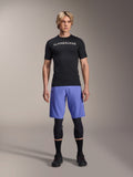 Alpinestars A-Aria Lite Short in Baja Blue, MTB-short voor heren, gedragen met een zwart shirt met korte mouwen en beschermende kniebeschermers, voorzien van laserperforaties voor ventilatie, mountainbike performance-uitrusting