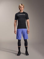 Alpinestars A-Aria Lite Short in Baja Blue, MTB-short voor heren, gedragen met een zwart shirt met korte mouwen en beschermende kniebeschermers, voorzien van laserperforaties voor ventilatie, mountainbike performance-uitrusting